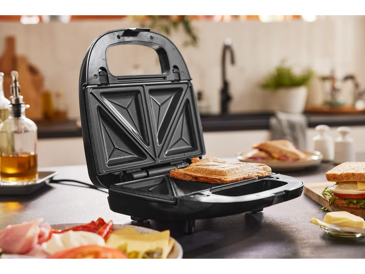 A SilverCrest Kitchen Tools 3-in-1 sandwich toaster with a toasted sandwich inside.