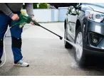 Man washing car with a cordless pressure washer.