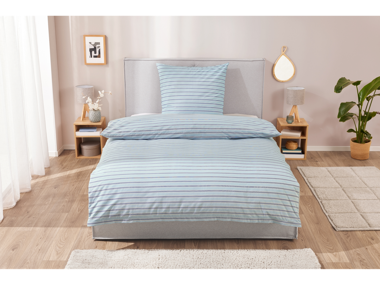 Gestreiftes Bettwäsche-Set in Blau- und Grautönen auf einem Bett.