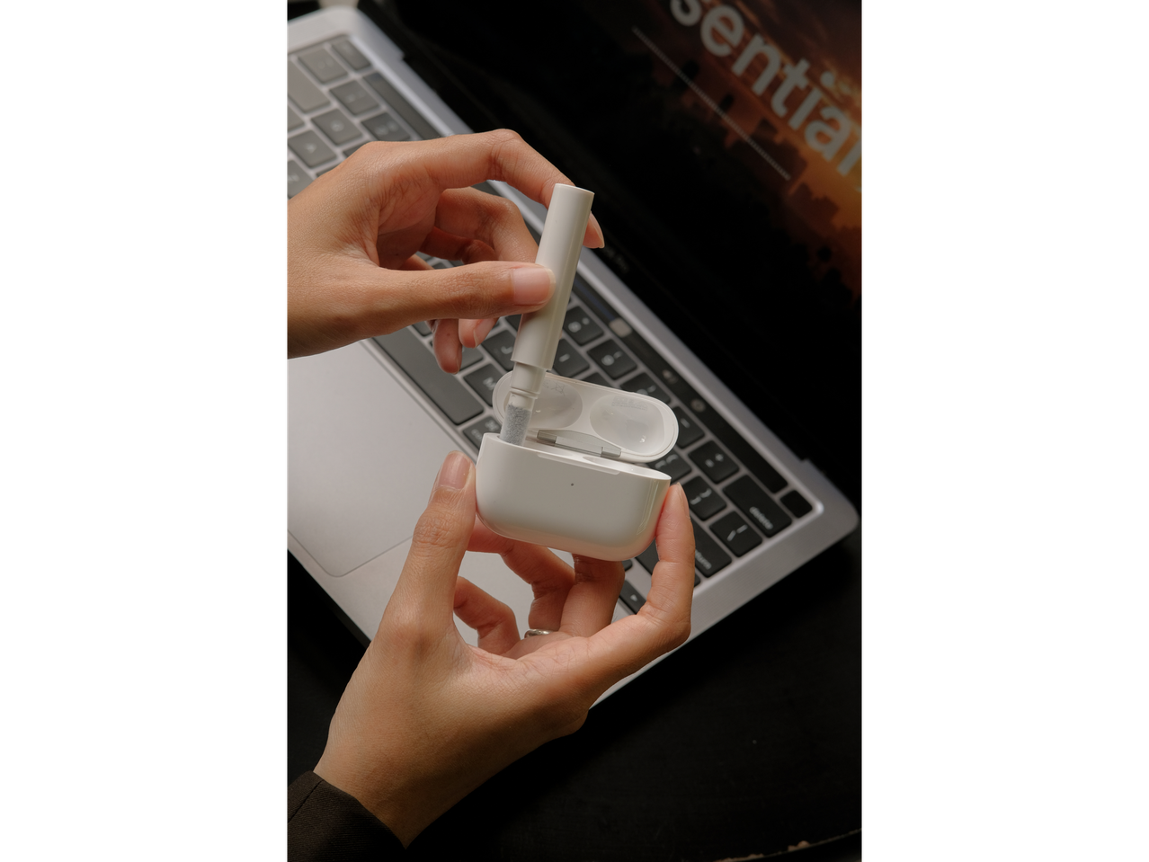 Mãos usando uma ferramenta de limpeza para fones de ouvido sem fio em um estojo de carregamento.