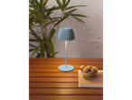 A light blue lamp on a wooden table with a bowl of cookies and papers.