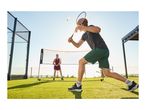 Two people playing badminton outdoors on artificial grass, with a net and rackets.