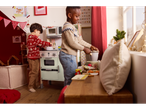 Two boys playing with a Lupilu wooden appliance play set in a festive room.