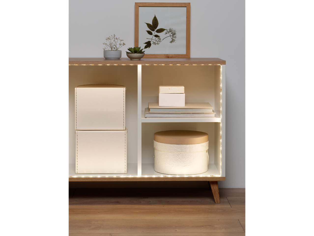 Iluminare LED sub un mobilier modern cu cutii și decorațiuni.