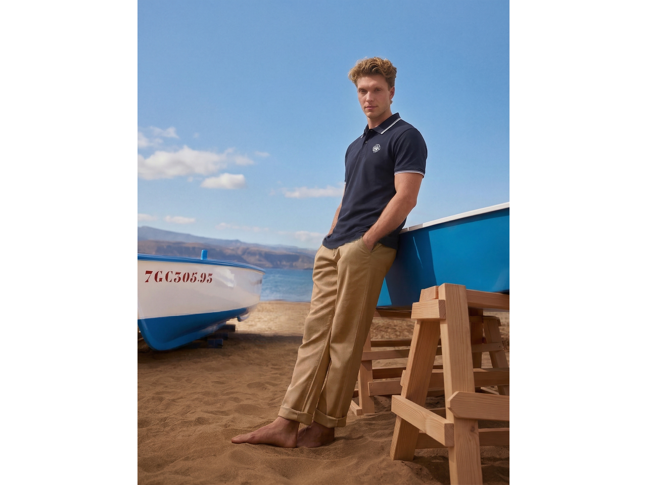 Homem com polo piqué ESMARA MEN azul-marinho e calças cáqui na praia.