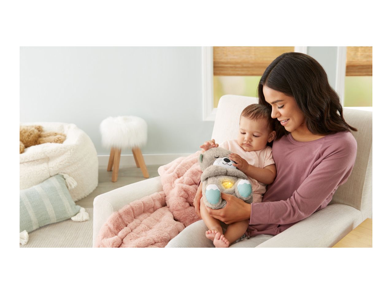 Mother and baby holding a plush otter toy with a glowing belly, sitting on a chair.