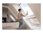 Woman cleaning a skylight window with a window vacuum cleaner in a modern kitchen.