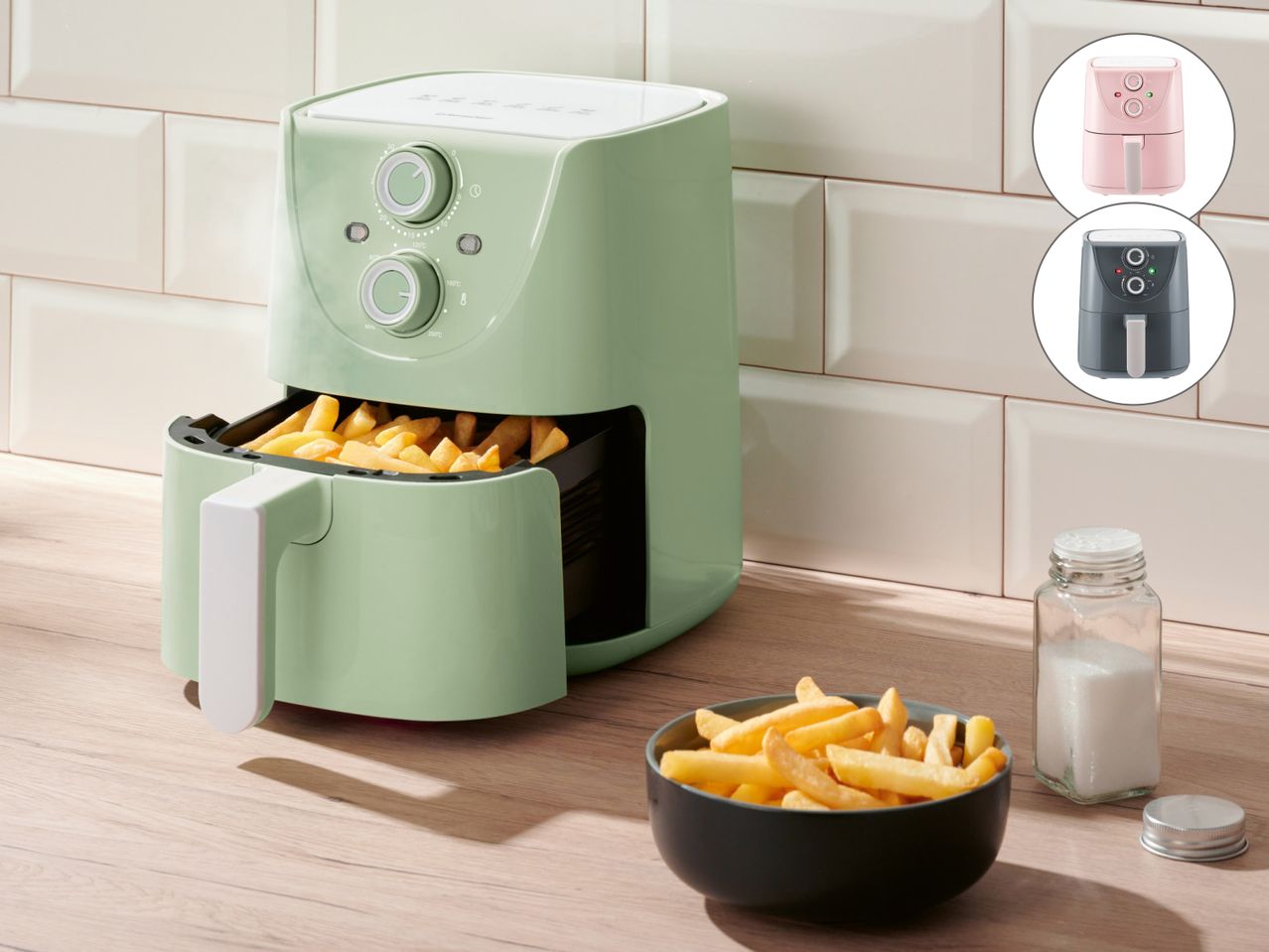 Zelena friteza na vrući zrak s pomfritom, posudom za sol i zdjelom pomfrita.