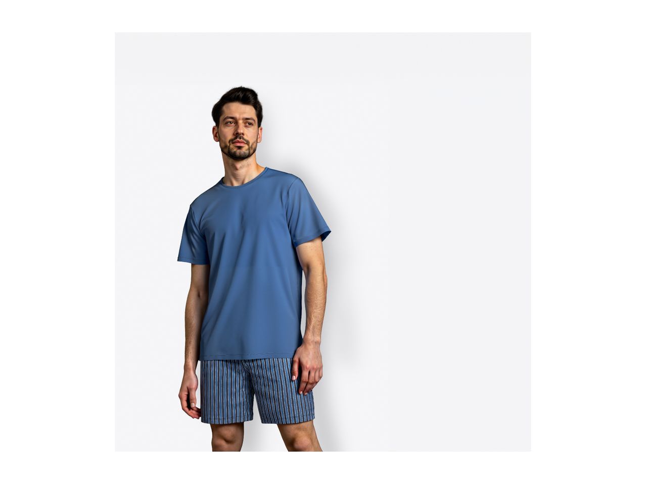 Man wearing a blue t-shirt and striped boxer shorts.