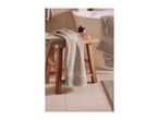 Bathroom with a wooden stool, green towels, a bath mat, and a diffuser.
