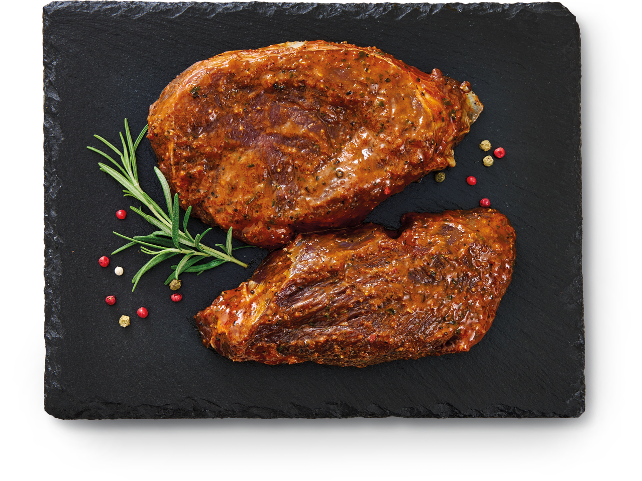 Divi marinēti gaļas gabali ar rozmarīnu un pipariem uz melna šīfera dēļa.