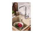 Kitchen sink with a chrome faucet, radishes in a colander, and wooden cutting boards.