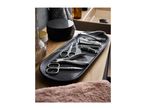 Manicure set with various tools on a black marble tray next to a sink.