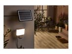 Solar-powered outdoor spotlight illuminating a patio area at dusk.