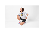 Woman in white t-shirt with blue trim and logo, black cycling shorts with logo, and sneakers.