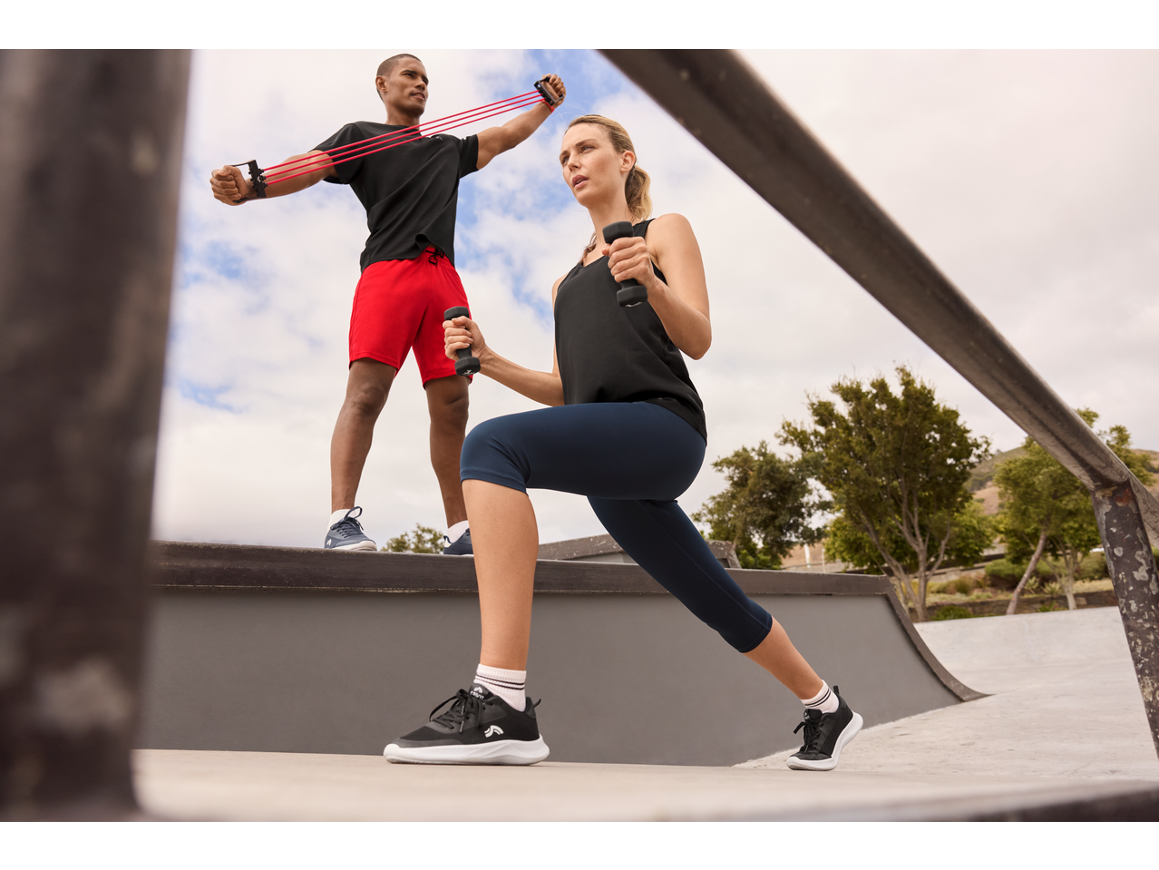 Woman in CRIVIT cropped sports leggings and man exercising outdoors.
