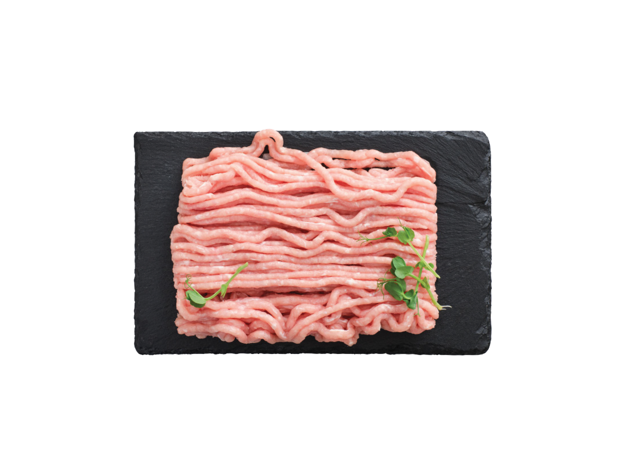 Šviežia malta kalakutiena ant juodos lentelės su žaliais daigais.