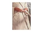 Close-up of a person tying a soft, cream-colored bathrobe around their waist.