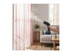 Handheld garment steamer in use on pink curtains in a living room.