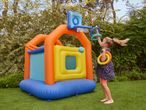 Child playing with an inflatable bouncy castle with a basketball hoop and ring toss.
