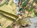 Férfi metszőollóval vágja a faágakat, fűrész és metszőolló látható.