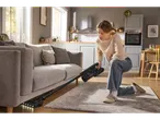 Жена почиства под дивана с безжична прахосмукачка Silvercrest® 2 в 1.