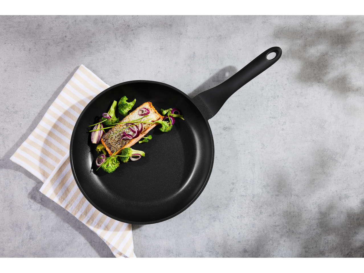 Silvercrest® pan with salmon, broccoli, and red onion on a gray surface.