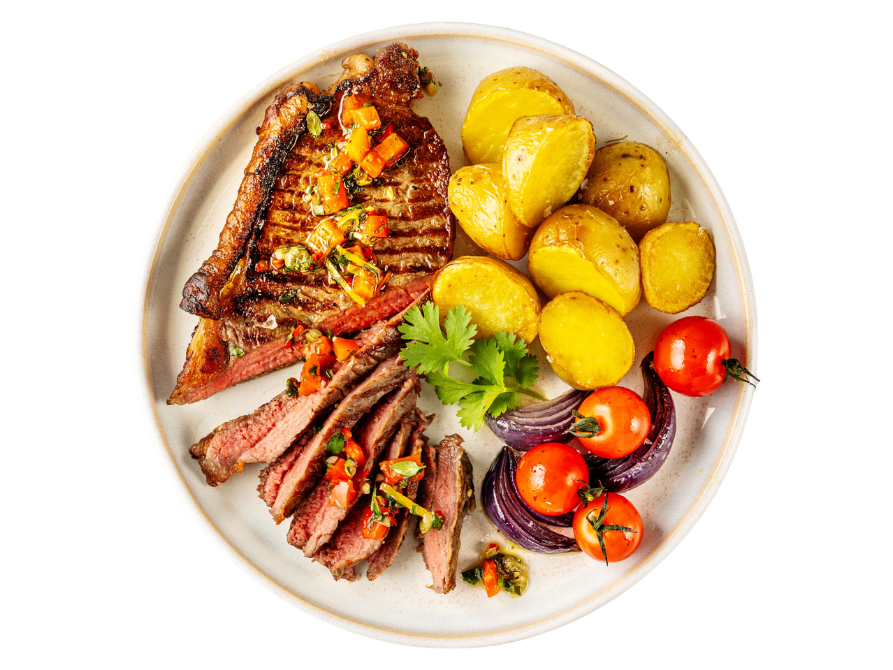 Grilled steak with roasted potatoes, tomatoes, and red onions on a white plate.