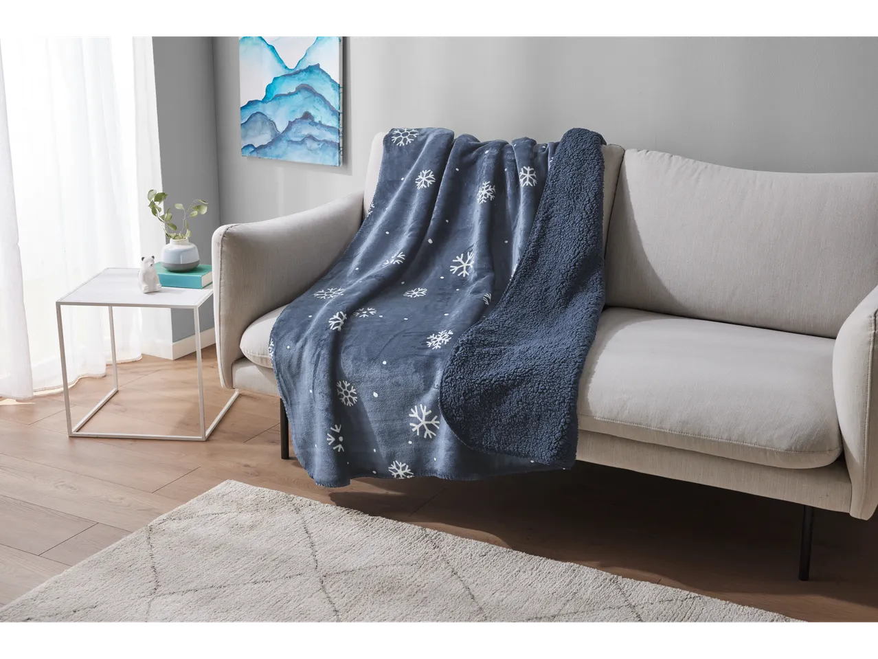 LIVARNO home snowflake blanket draped over a light-colored sofa in a living room.