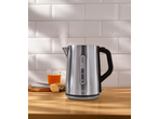 Steaming electric kettle on a wooden counter with a cup of tea and cookies.
