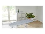 Ironing board with a geometric pattern cover in a bright room with a large window.