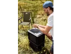 Man washing hands at a portable sink, with a CRIVIT folding camping chair nearby.