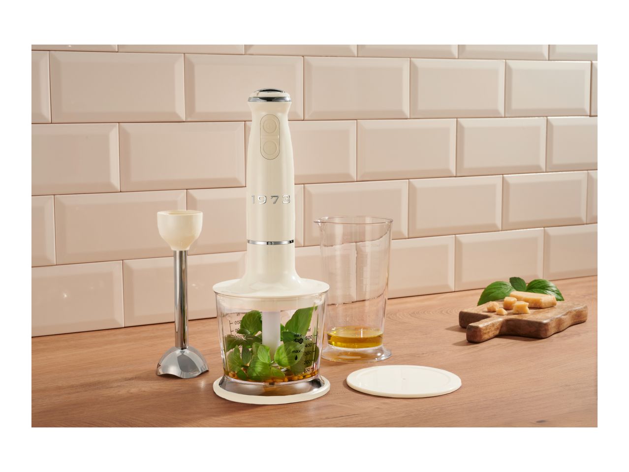 Retro-style hand blender set with chopper, beaker, and blending attachment on a wooden countertop