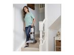 Woman carrying a Vax carpet cleaner down carpeted stairs.