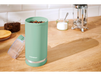 Moedor de café SilverCrest verde-menta com grãos de café, em uma mesa de madeira.