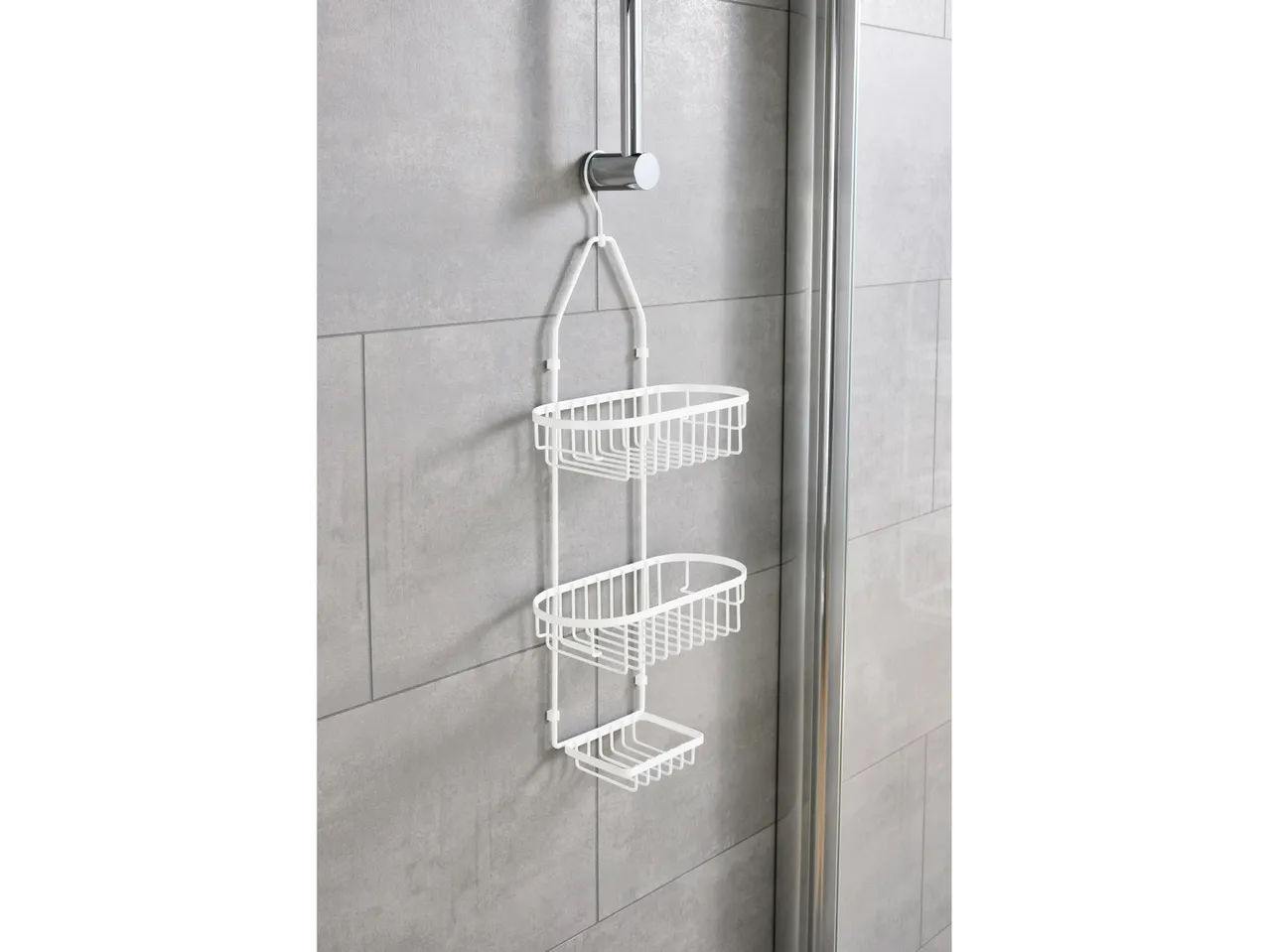 White three-tiered shower Rack hanging on a shower door.