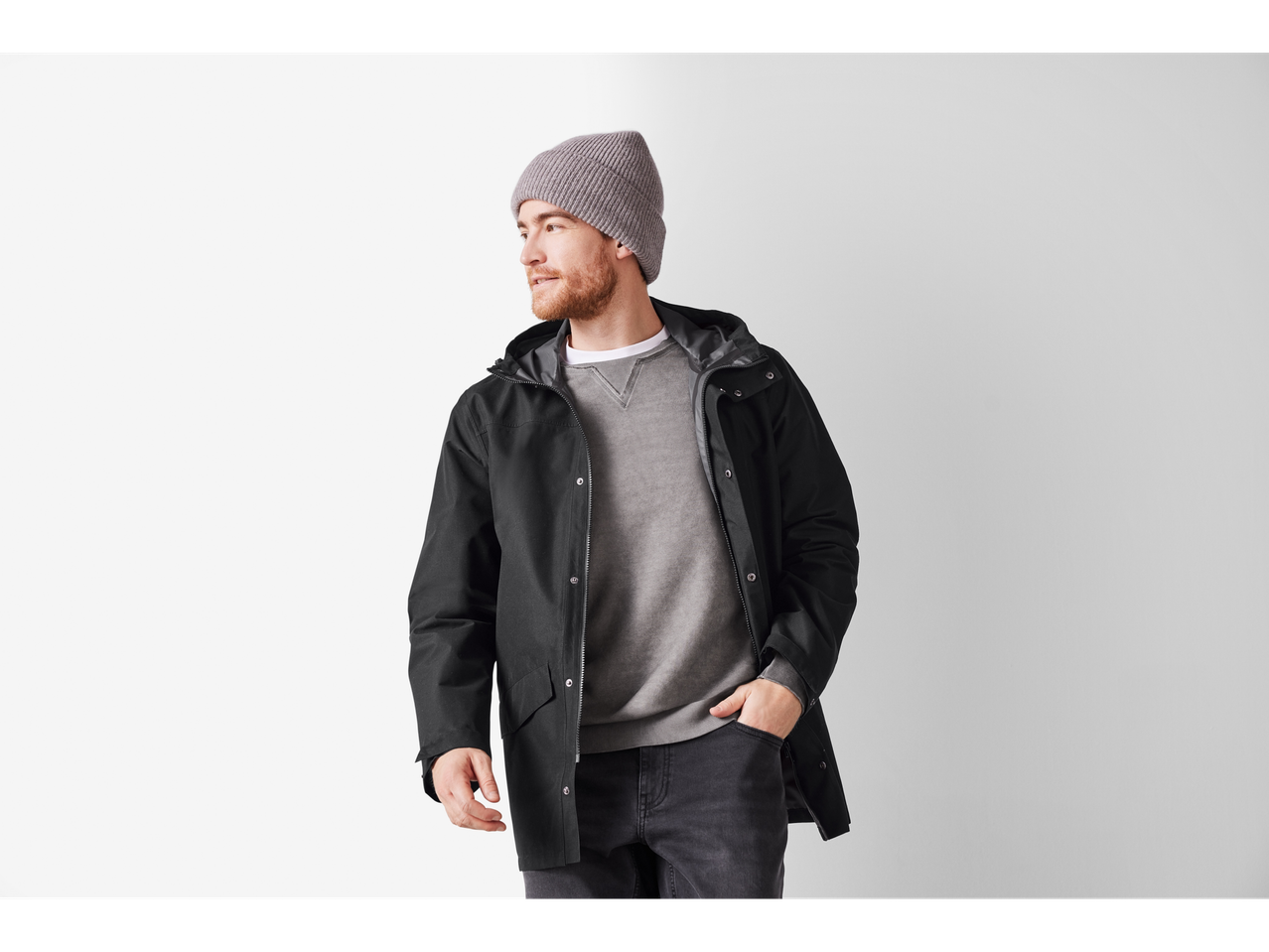 Man in a black rain jacket, grey sweatshirt, and grey beanie.