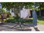 Clothes drying rack with various garments, including shirts, pants, and a denim jacket, outdoors.