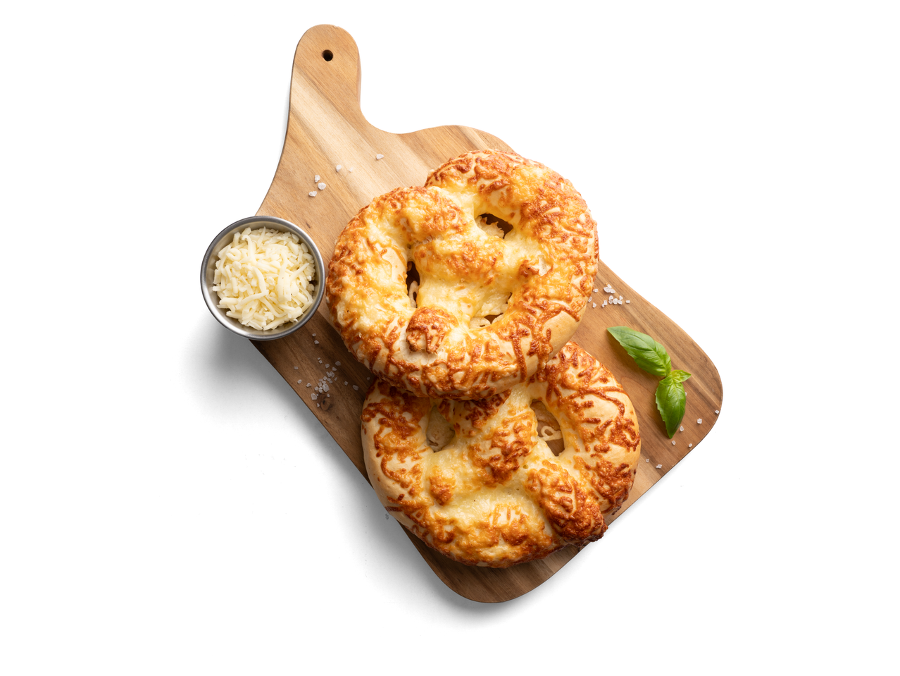 Két sajtos perec vágódeszkán reszelt sajttal és bazsalikommal.