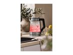 Glass kettle with red illuminated water and ice, next to a glass with lemon slices.