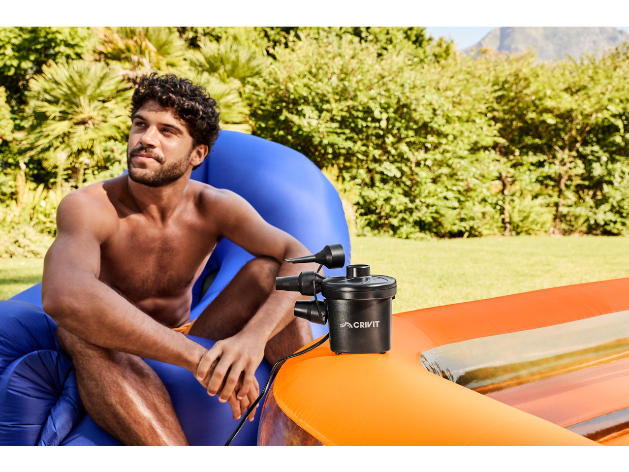 Bărbat cu pompă electrică lângă o piscină gonflabilă CRIVIT