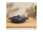 Black cast iron Dutch oven on a wooden countertop with a plant.