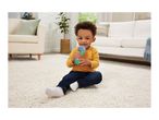 Toddler boy playing with a toy microphone on a fluffy white rug in a living room.