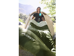 Woman with CRIVIT sleeping bag and tent, mountains in background.