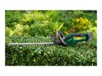 Cordless hedge trimmer on a freshly trimmed green hedge in a garden.