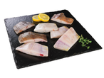 Filetes frescos de linguado em pedra preta, decorados com fatias de limão e tomilho.