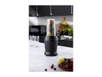 Black blender filled with fruit on a kitchen counter with two glasses and a fruit bowl.