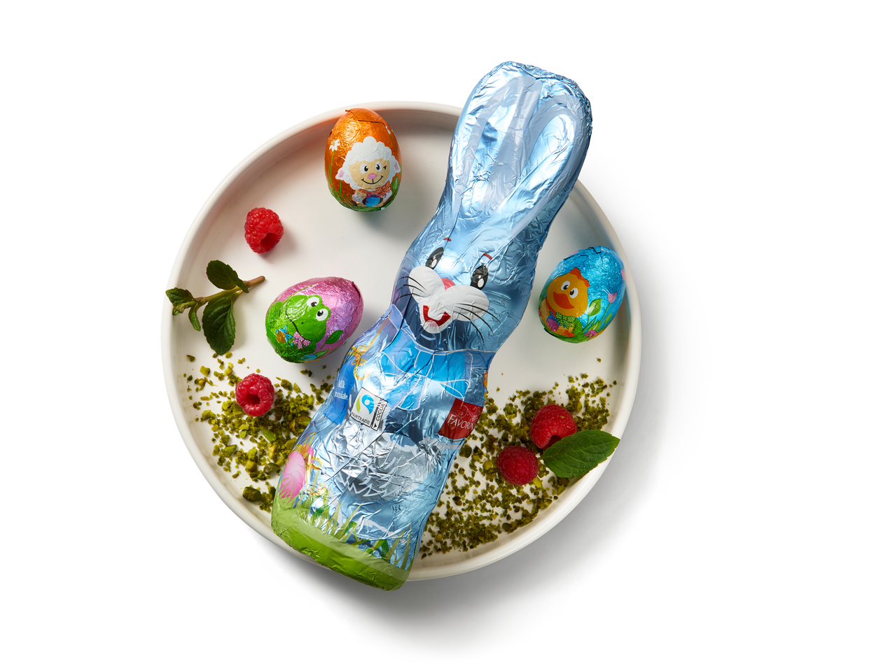 Blue foil-wrapped chocolate bunny with three foil-wrapped chocolate eggs on a plate.