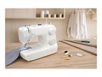 A white sewing machine on a wooden table with sewing accessories and fabric.