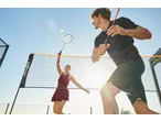 Duas pessoas a jogar badminton com um conjunto de badminton CRIVIT sob o sol.